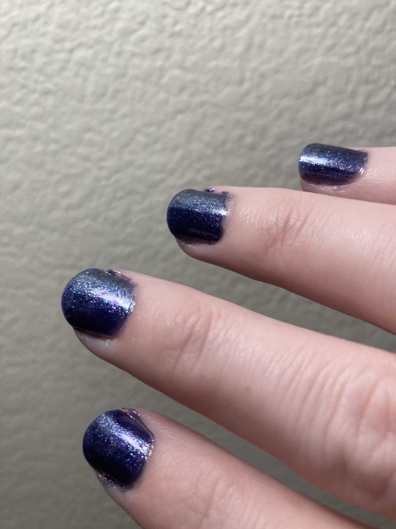 Essie #1657 “Broom with a View”, a dark blue polish with fine green, pink, and purple glitter.